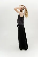 Falda larga negra, estilo envolvente o pareo, con abertura frontal alta y lazo ajustable en la cintura.