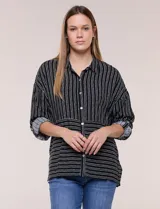 Camisa de rayón negra con patrón de líneas blancas. Presenta cuello camisero, cierre frontal con botones, mangas largas con puños vueltos y un diseño con corte horizontal que alterna líneas verticales en la parte superior y horizontales en la inferior.