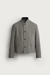 Blazer cropped de corte ajustado con estampado de cuadros, cuello mao y manga larga. Cuenta con bolsillos con solapa en la cadera y cierre frontal de botones.