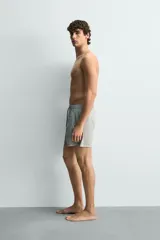 Short de baño confeccionado en tejido técnico con patrón de rayas verticales en tonos azul marino y blanco, con cintura elástica ajustable mediante cordón y bolsillos laterales.