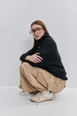 Pantalón cargo negro de corte relajado y pierna ancha con bolsillos laterales con solapa, cintura con doble broche y cierres metálicos en los tobillos.