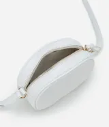 Cartera tipo camera bag pequeña, color marrón camel, de forma ovalada con superficie texturizada. Cuenta con correa ajustable larga, cierre principal con cremallera dorada y un pequeño bolsillo frontal con cremallera.