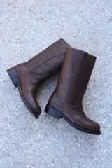 Bota de cuero marrón con caña media, puntera redondeada y detalle de costuras.