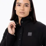 Buzo polar de mujer con cuello alto y cierre frontal parcial con botones a presión. Presenta un diseño de manga larga con puños elásticos y un parche con logo en el pecho.