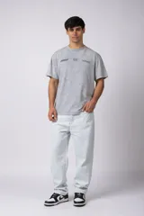 Remera de algodón con efecto de lavado snow-wash en color gris. Presenta un diseño de cuello redondo, mangas cortas y un estampado frontal minimalista con gráficos de estilo automovilístico y cuadros de meta.