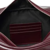 Bolso tipo barrel o doctor bag de cuero charol color vino tinto. Presenta dos asas superiores con detalle de trenzado y ojales metálicos, y múltiples tiras largas de cuero colgando de los herrajes circulares frontales. Incluye correa ajustable para llevar al hombro.