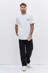 Remera de manga corta color blanco, con cuello redondo y pequeño parche rectangular con diseño de rayas verticales en el pecho.