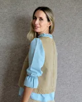 Chaleco de corte recto y largo a la cintura, confeccionado en denim con estampado de rayas verticales en tonos azul y blanco. Presenta cuello redondo y costuras visibles que definen su estructura.