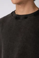 Remeron de corte oversized con cuello redondo y mangas cortas. Presenta un acabado de tela con efecto desgastado y costuras visibles en los bordes, con una etiqueta pequeña en el lateral inferior.