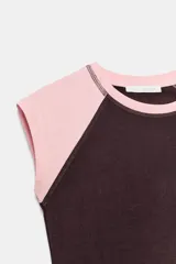 Camiseta de corte ajustado con diseño de mangas tipo raglán en color rosado y cuerpo en color marrón oscuro. Presenta cuello redondo y bajo recto.