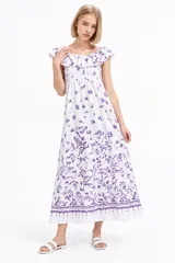 Vestido largo de algodón blanco con estampado floral en tonos violeta, diseño holgado, escote bote con volados y detalle fruncido en el pecho.