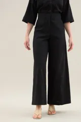 Pantalon largo de lino color tostado, tiro alto, corte ancho y recto, con costuras centrales decorativas y bolsillos laterales.