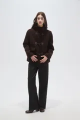 Campera tipo duffle coat de paño color marrón oscuro, con capucha, cierre frontal mediante tres trabas de madera y cuero, y bolsillos delanteros con solapa.