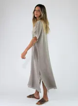 Vestido largo azul de algodón, con escote en V, mangas cortas amplias y detalles de flecos en los bordes, cuello y aberturas laterales.