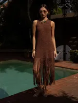 Vestido corto tejido a mano en crochet, color marrón con destellos metalizados. Presenta escote redondo, diseño sin mangas y un ruedo con flecos largos que aportan movimiento.