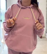 Canguro deportivo de tela suave con logo bordado, diseño holgado y mangas largas.