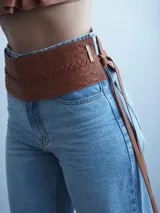 Faja de cuero color camel con diseño trenzado horizontal y lazo lateral ajustable con flecos.