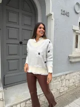 Buzo color blanco con cuello en V, mangas largas y estampado de lunares negros.