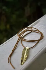 Collar con dije de hoja dorada y cordón marrón.