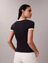 Remera Calvin Klein de corte baby fit y manga corta, confeccionada en tejido acanalado negro. Presenta cuello redondo y puños con ribetes en contraste blanco y amarillo fluo, y el logo de la marca bordado en el pecho.