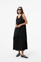 Vestido largo negro de silueta relajada, con escote en V y diseño en capas que aporta movimiento.