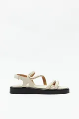 Sandalias color beige con plataforma negra, tiras trenzadas y ajuste con velcro en el talón.