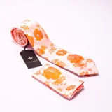 Conjunto de corbata y pañuelo de bolsillo Florenzi con estampado floral en tonos naranja y amarillo sobre fondo rosa. El pañuelo mide 27x27 cm.