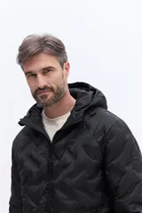 Campera de nylon matelaseada con capucha integrada, cierre frontal y diseño de costuras geométricas. Presenta un ajuste regular y es ideal para climas fríos.