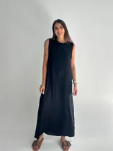 Vestido negro largo de tela satinada, sin mangas y con cuello redondo.