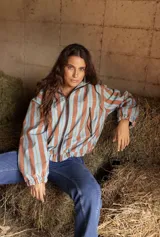 Campera impermeable con cierre frontal, diseño de rayas verticales en tonos celestes y marrones, cuello alto y puños elásticos.