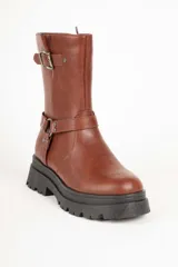 Bota biker negra de símil cuero, con punta redonda y apliques de tachas, hebilla y argolla. Plataforma tractor de 5cm y cierre lateral.