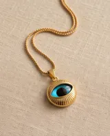 Collar de bronce dorado con cadena fina y dije redondo en relieve con diseño de ojo turco esmaltado en tonos azul y negro.