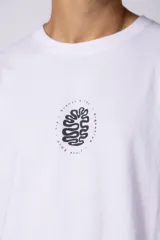 Remera oversize de corte holgado, color blanco, con cuello redondo y mangas cortas. Presenta un pequeño estampado circular en el centro del pecho con un diseño abstracto inspirado en arrecifes.