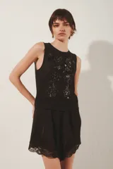 Top sin mangas de mesh con escote redondo y bordados florales hechos a mano a tono. Presenta un diseño sin forrería.