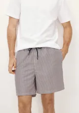 Short de baño blanco con estampado de hojas negras, cintura elástica y bolsillos laterales.