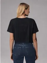 Remera tipo crop top de algodón color negro, con cuello redondo, mangas cortas y estampa minimalista en el pecho.