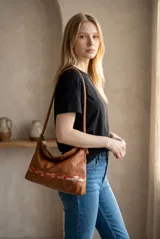 Cartera de cuero 100% natural color marrón, con diseño de hombro, cierre superior y detalles de arte pintado en la parte inferior.