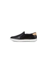 Zapatilla tipo slip-on de cuero negro, con perforaciones en el cuerpo y detalle de cuero color camel en el talón. Posee suela blanca gruesa y elásticos laterales para ajuste.