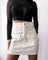 Minifalda blanca de cuero sintético con bolsillos tipo cargo y cinturón incluido.