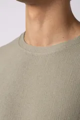 Remera de corte oversize confeccionada en tejido texturado tipo lino, de color beige, con cuello redondo amplio y mangas cortas de calce relajado.