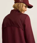 Campera rompevientos deportiva de mujer, marca Get Over, color beige con sutiles rayas verticales, cuello alto, cierre frontal con cremallera y puños ajustados.
