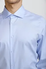 Camisa de vestir blanca de corte clásico, con cuello rígido, cierre frontal de botones y mangas largas con puños abotonados.