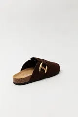 Zueco de estilo casual con capellada cerrada en material tipo gamuza color negro. Presenta una hebilla metálica decorativa en tono dorado sobre el empeine y una base anatómica con efecto corcho.