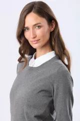 Buzo de tejido de punto fino en color gris, con cuello redondo a la base y mangas largas. Presenta un diseño de calce clásico y versátil.