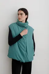 Chaleco puffer con cuello alto y cierre frontal oculto, estampado con diseño floral y de aves en tonos rojos sobre base azul oscuro.