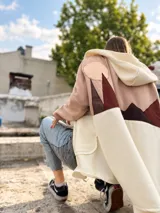 Campera con capucha de calce amplio, diseño en bloques de color beige, rosado y marrón, con aplique textil en la espalda que simula un paisaje montañoso. Cuenta con cierre delantero y bolsillos.