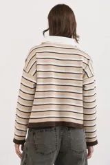 Sweater tipo chomba de tejido bremer, con diseño de rayas horizontales en tonos beige, blanco y marrón chocolate. Presenta cuello polo con cierre frontal de botones y mangas largas.