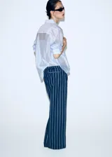 Pantalón de corte recto y tiro regular, confeccionado en algodón con diseño de rayas verticales. Presenta cintura elástica con cordón ajustable y bolsillos laterales.