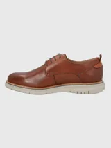 Zapato de vestir Hush Puppies modelo Rustic, confeccionado en cuero color marrón con cordones al tono. Presenta una suela de EVA en color gris claro con detalle de marca FLX en el lateral.