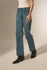 Pantalon de corte recto y tiro medio, confeccionado en denim color gris oscuro. Presenta bolsillos delanteros decorados con tachas metálicas pequeñas en los bordes y cierre frontal con botón y cremallera.